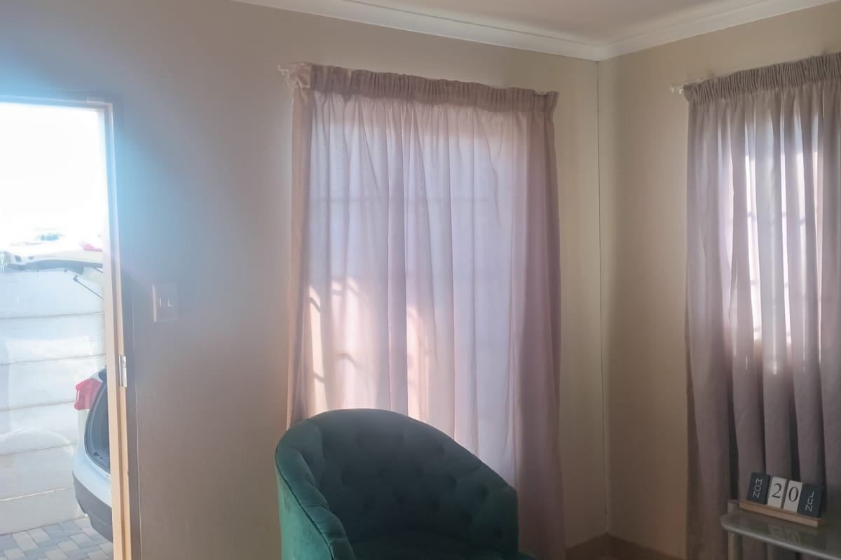 A living room area featuring tiled flooring and coved ceilings, with direct access to the exterior driveway.
