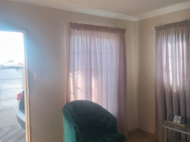 A living room area featuring tiled flooring and coved ceilings, with direct access to the exterior driveway.