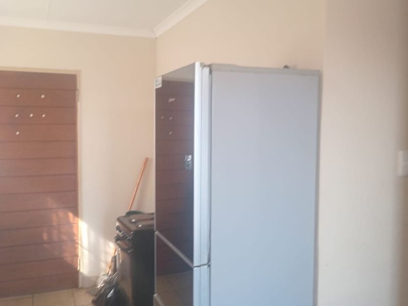 A functional kitchen area featuring tiled flooring, coved ceilings, and a solid core door, providing a practical layout for daily use.