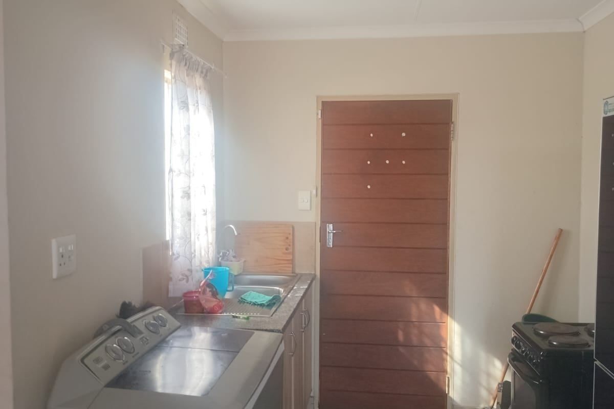 A functional kitchen area featuring tiled flooring, a stainless steel sink, and built-in cabinetry, providing a practical space for daily household tasks.