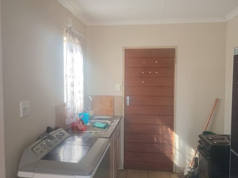 A functional kitchen area featuring tiled flooring, a stainless steel sink, and built-in cabinetry, providing a practical space for daily household tasks.