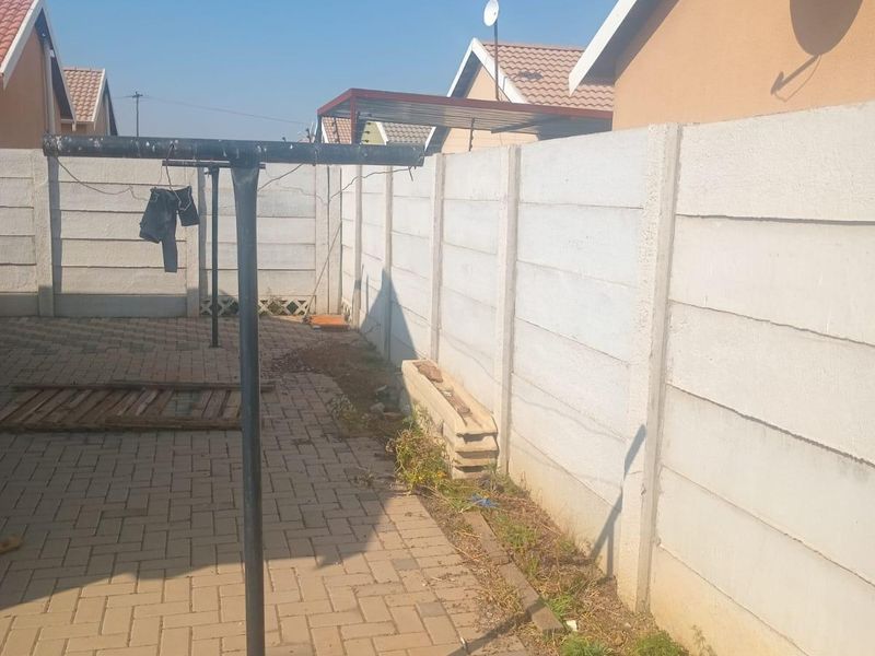 A paved rear courtyard area enclosed by precast concrete boundary walls, featuring a rotary clothesline and satellite dish installation.