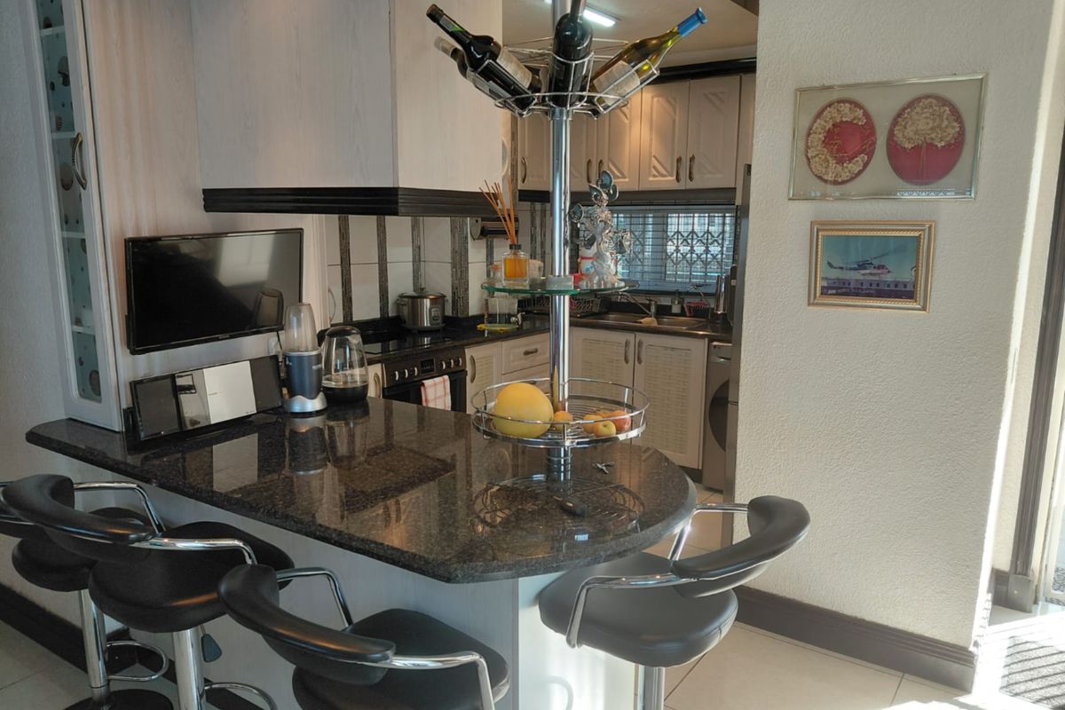 A functional kitchen featuring a granite breakfast bar, built-in cabinetry, and integrated appliances, offering a practical layout for daily cooking and dining.