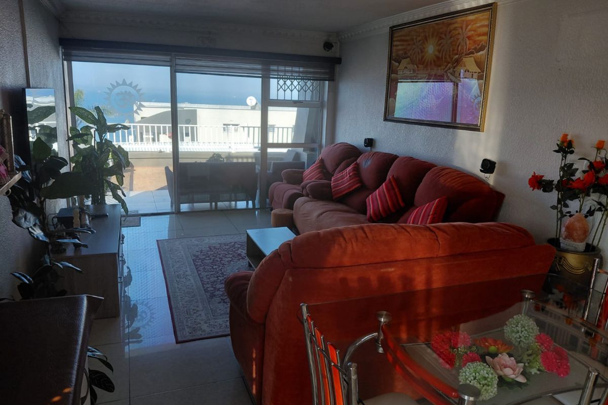 A living room featuring tiled flooring and a large sliding glass door that provides access to an outdoor balcony area.