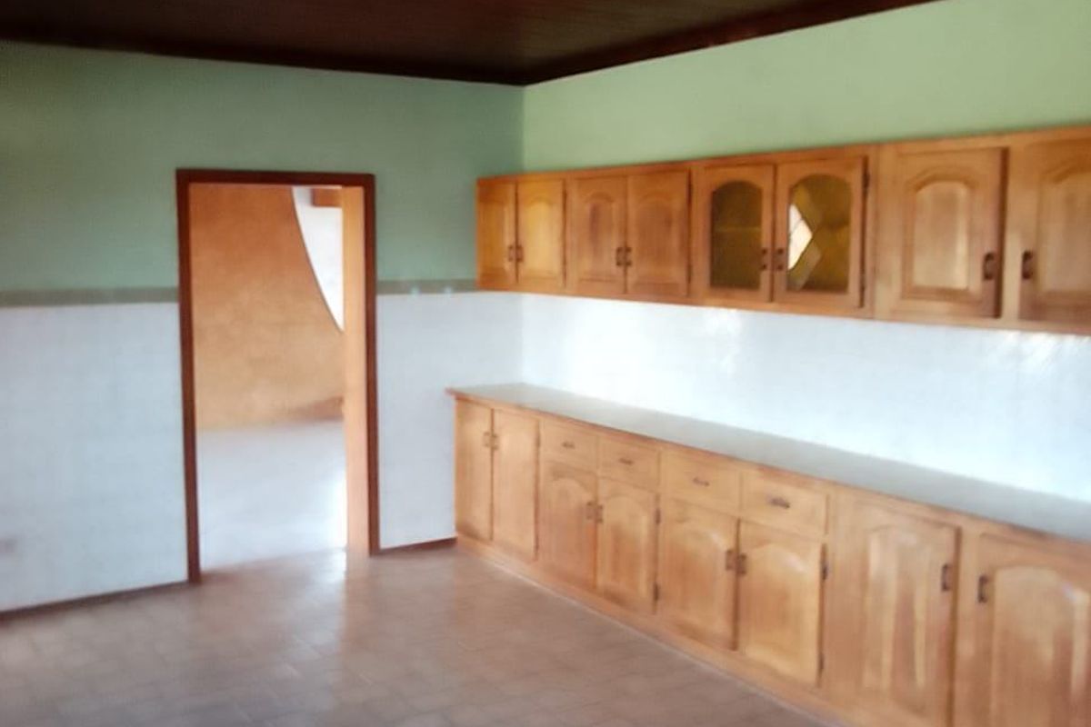 A spacious kitchen featuring extensive wooden cabinetry, tiled splashbacks, and a timber ceiling, offering a functional layout ready for modernization.