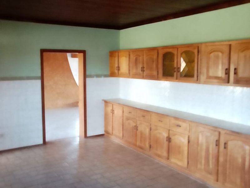 A spacious kitchen featuring extensive wooden cabinetry, tiled splashbacks, and a timber ceiling, offering a functional layout ready for modernization.