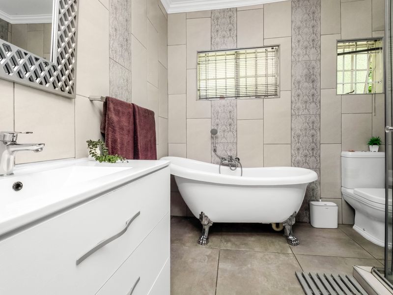 A well-maintained bathroom featuring a classic clawfoot bathtub, modern vanity with basin, toilet, and a separate shower enclosure with neutral tiled finishes.