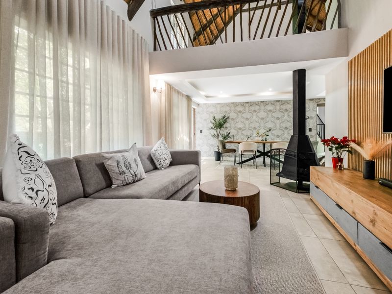 Spacious open-plan living area featuring a modern freestanding fireplace, vaulted ceilings, a mezzanine level, and stylish timber slat wall detailing.