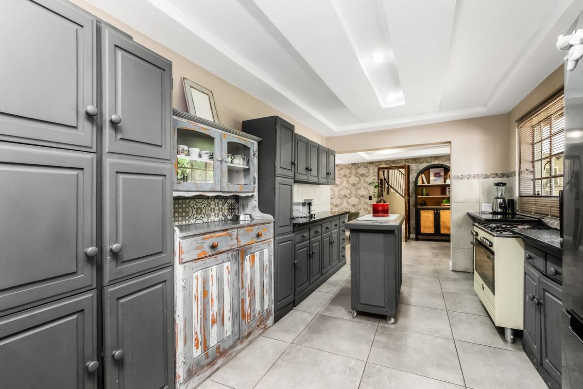 A kitchen featuring dark grey cabinetry, a central island, gas stove, and tiled flooring, with a distinct rustic-style hutch and recessed ceiling lighting.