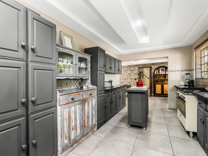 A kitchen featuring dark grey cabinetry, a central island, gas stove, and tiled flooring, with a distinct rustic-style hutch and recessed ceiling lighting.