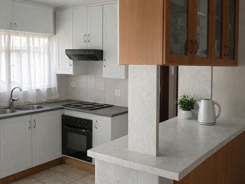 Functional kitchen featuring white cabinetry, laminate countertops, a breakfast bar, and integrated appliances including an electric hob and oven.