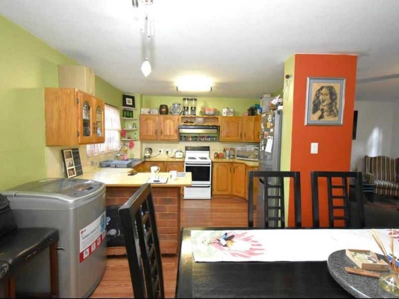 Open-plan kitchen and dining area featuring wooden cabinetry, laminate countertops, and a freestanding stove, with a functional layout connecting to the living space.