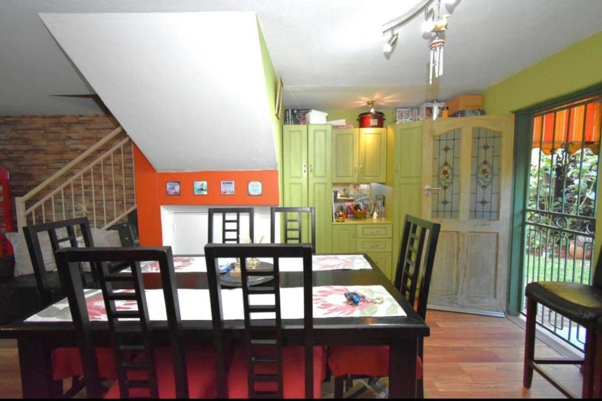 Open plan dining area featuring timber flooring, built-in cabinetry, and a staircase, with direct access to the outdoor patio area.