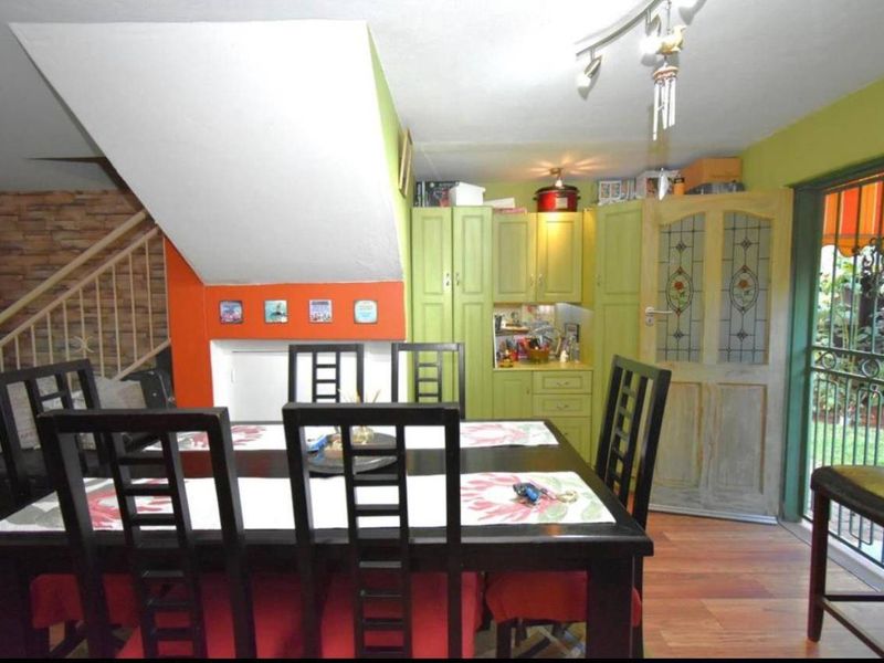 Open plan dining area featuring timber flooring, built-in cabinetry, and a staircase, with direct access to the outdoor patio area.