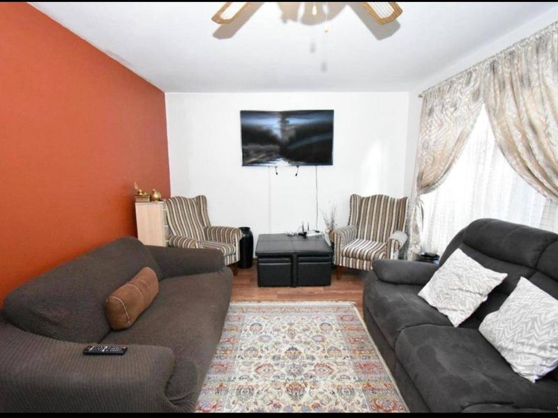 A comfortable living room featuring laminate flooring and a ceiling fan, providing a functional space for relaxation.