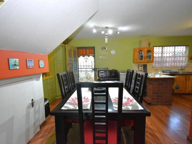 Open plan living and dining area featuring wooden flooring, a brick kitchen island, and direct access to an exterior security gate.