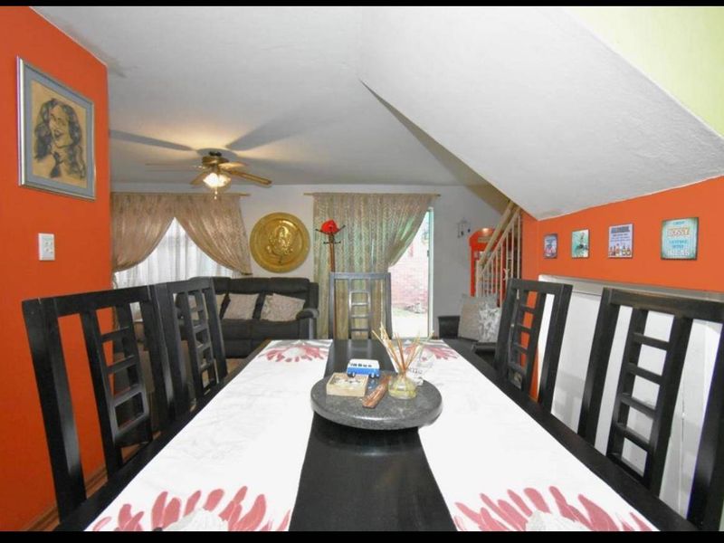 Dining area featuring a staircase and sliding glass door access to the exterior, with vibrant orange accent walls.