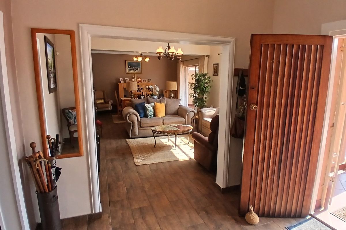 A view from the entryway looking into a living area featuring timber-look floor tiles and an open-plan layout connecting to the outdoor space.