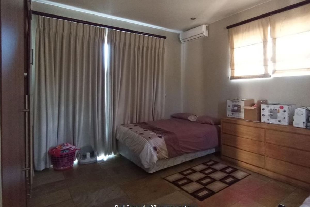 Spacious bedroom featuring tiled flooring, a built-in wardrobe, and a wall-mounted split-system air conditioner.
