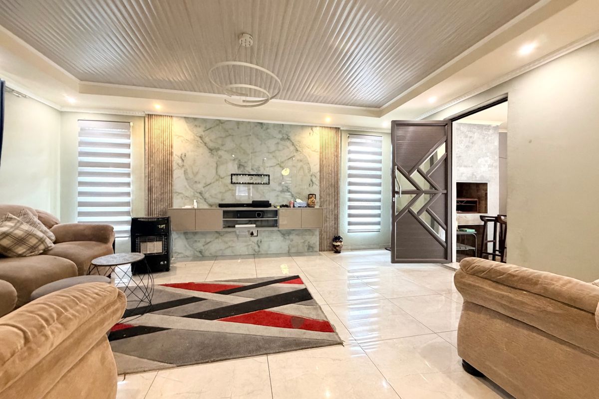 Spacious living room featuring a marble accent wall, floating media console, tiled flooring, and a modern recessed ceiling design.