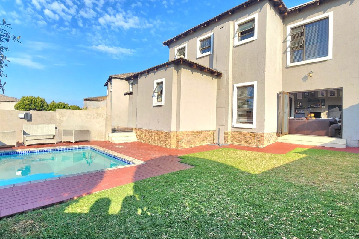 Rear view of the property featuring a swimming pool, paved patio area, and a well-maintained lawn with access to the interior living space.