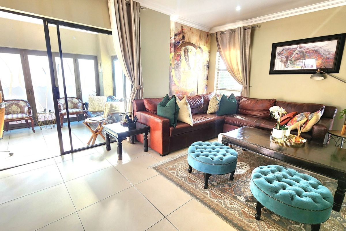 Spacious living room featuring large sliding glass doors that open onto a patio, complemented by neutral tiled flooring and recessed ceiling lighting.