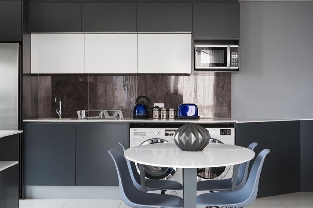 Modern kitchen featuring sleek dark and white cabinetry, stone splashback, integrated microwave, and high-quality finishes with recessed lighting.