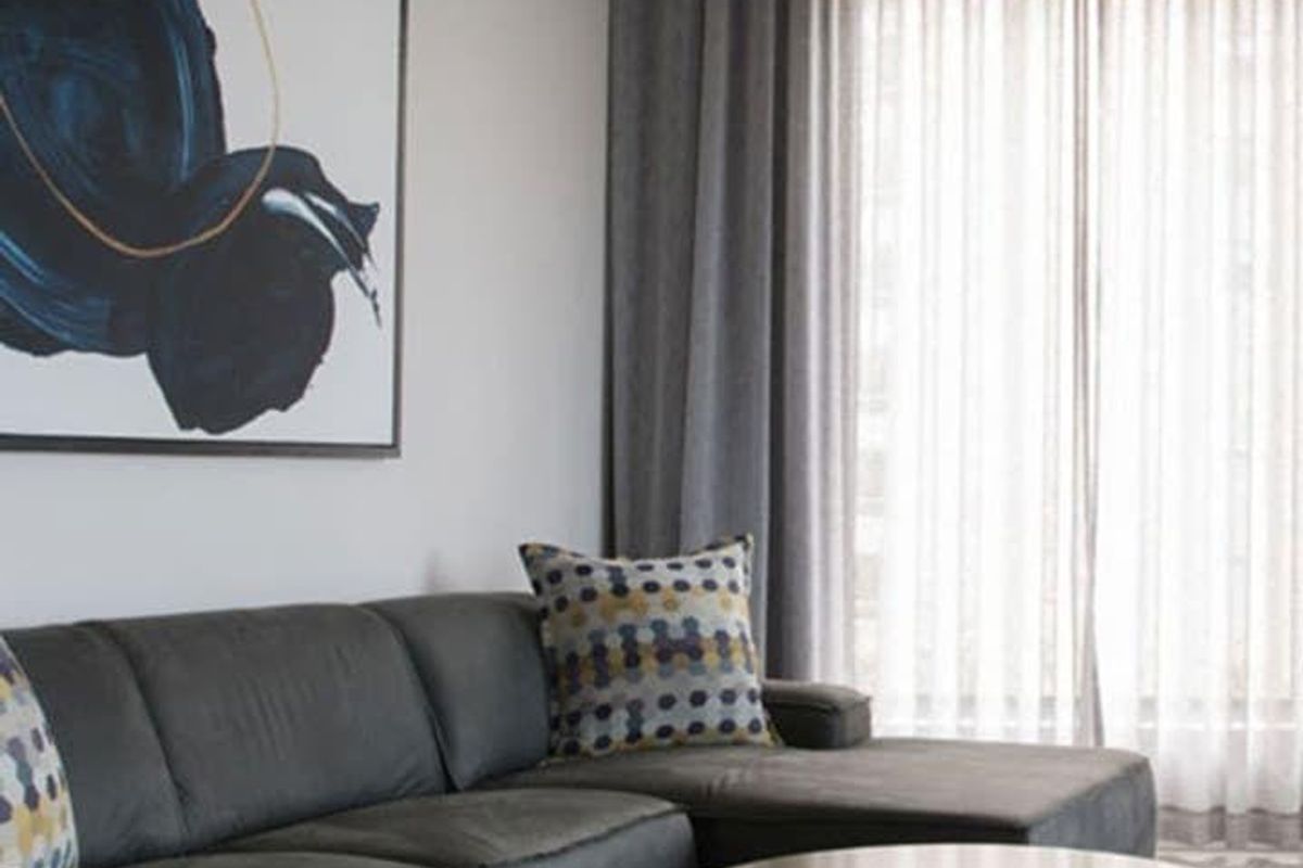 A modern living room featuring recessed ceiling lighting and floor-to-ceiling window treatments, creating a bright and comfortable atmosphere.