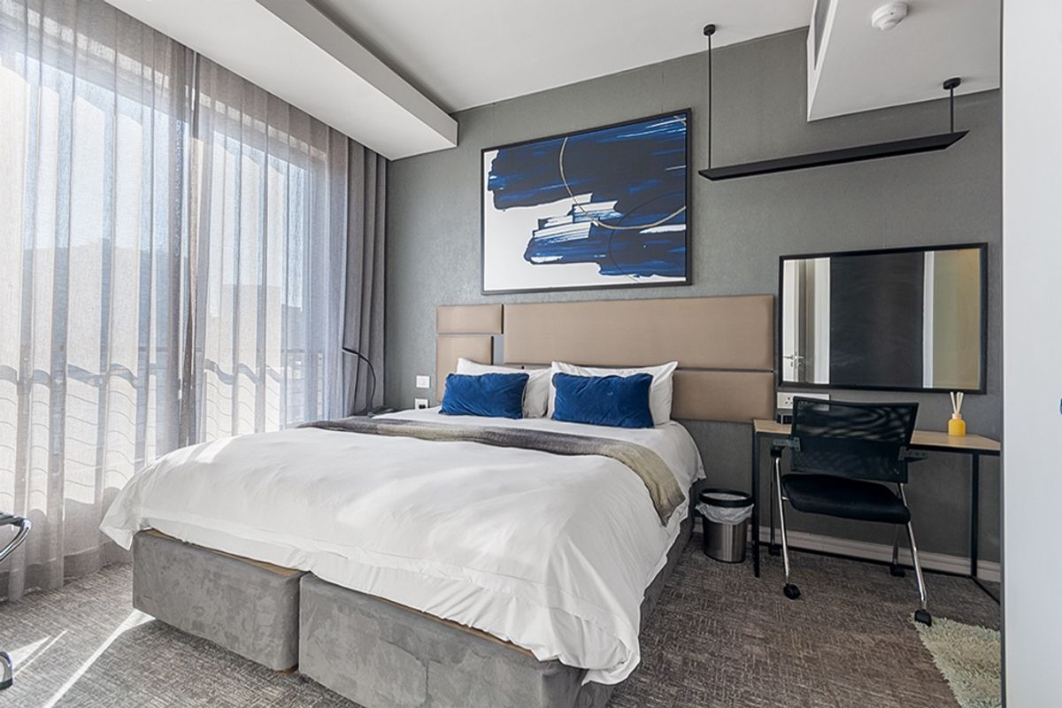Modern bedroom featuring a neutral color palette, upholstered headboard, recessed curtain tracks, and integrated lighting, creating a clean and contemporary living space.