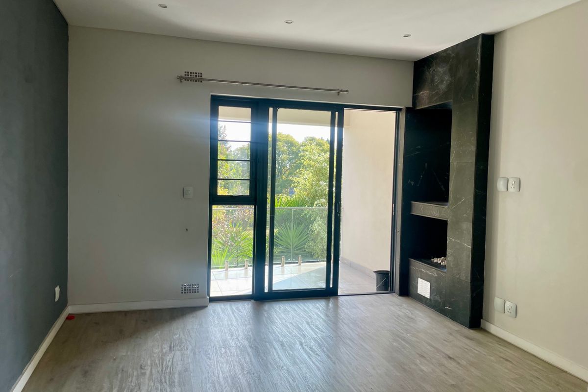 Bright living room featuring modern laminate flooring, a sleek built-in fireplace, and large sliding glass doors leading to a private balcony.