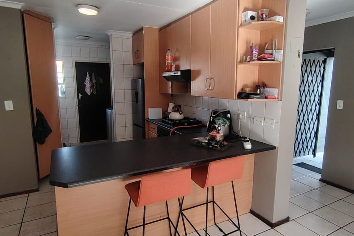 Functional kitchen featuring laminate cabinetry, a breakfast bar, tiled flooring, and a gas hob with an integrated extractor fan.
