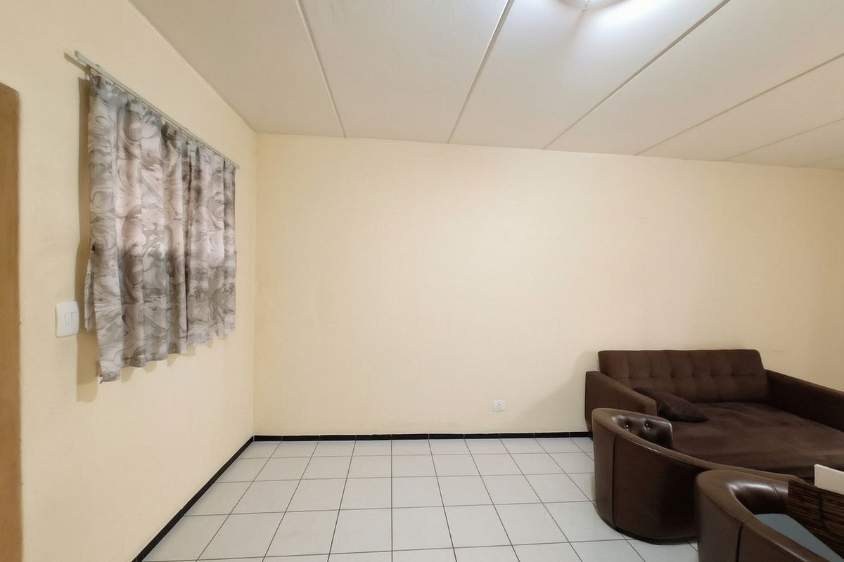 A living room area featuring tiled flooring and a suspended ceiling, providing a neutral base for interior design updates.