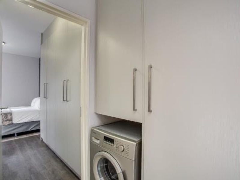 A compact laundry area featuring built-in cabinetry for storage, conveniently located adjacent to a bedroom.