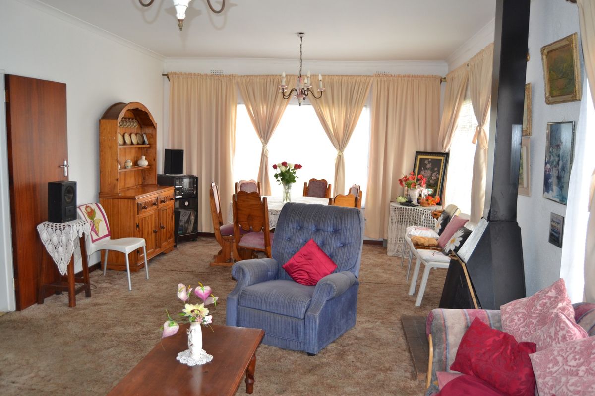 Spacious living room featuring a freestanding fireplace and carpeted flooring, offering a traditional layout with ample natural light.