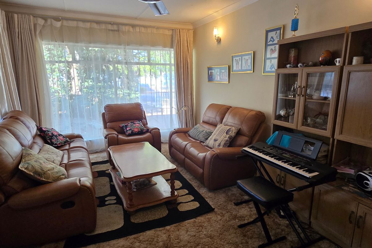 A comfortable living room featuring a large window, ceiling fan, and built-in cabinetry, providing a functional and well-lit space for relaxation.