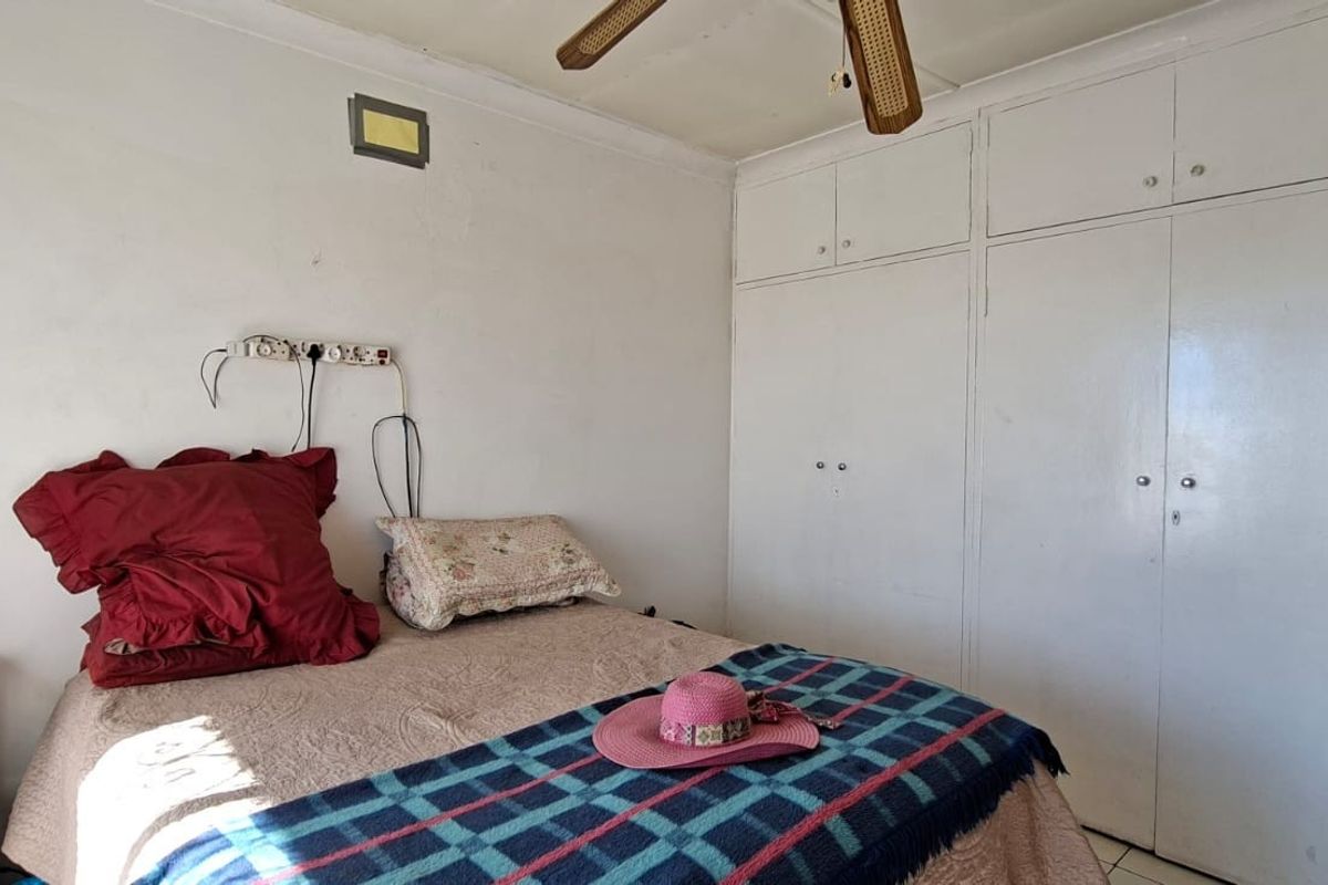 Bedroom featuring built-in cupboards and a ceiling fan, requiring cosmetic updates and electrical repairs to improve the overall finish.