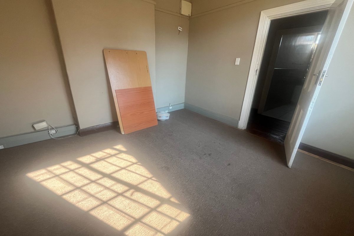 An empty bedroom featuring carpet flooring, neutral wall tones, and direct access to an adjoining room.