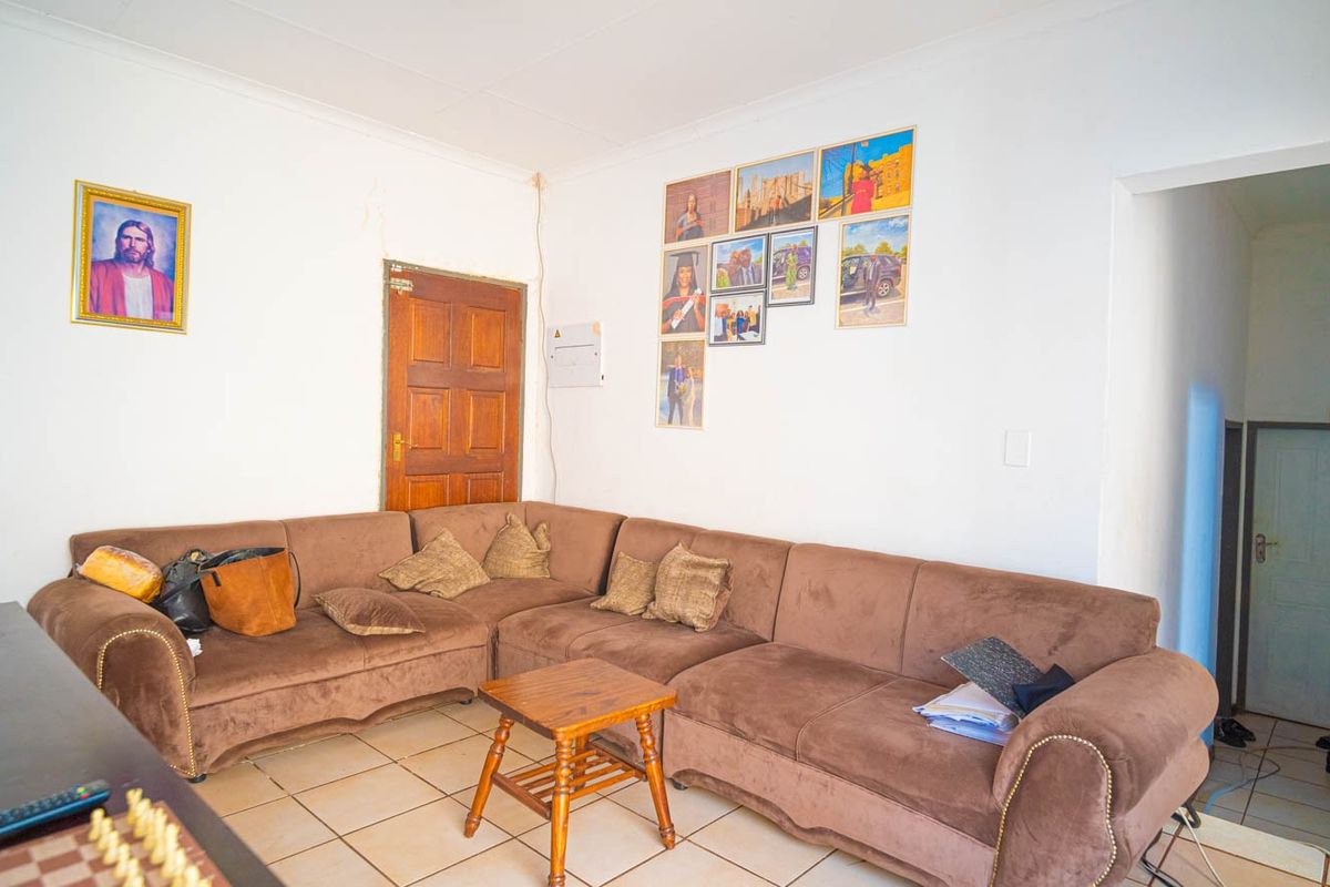 A living room area featuring tiled flooring and a timber door, with visible wall plaster cracking near the door frame.