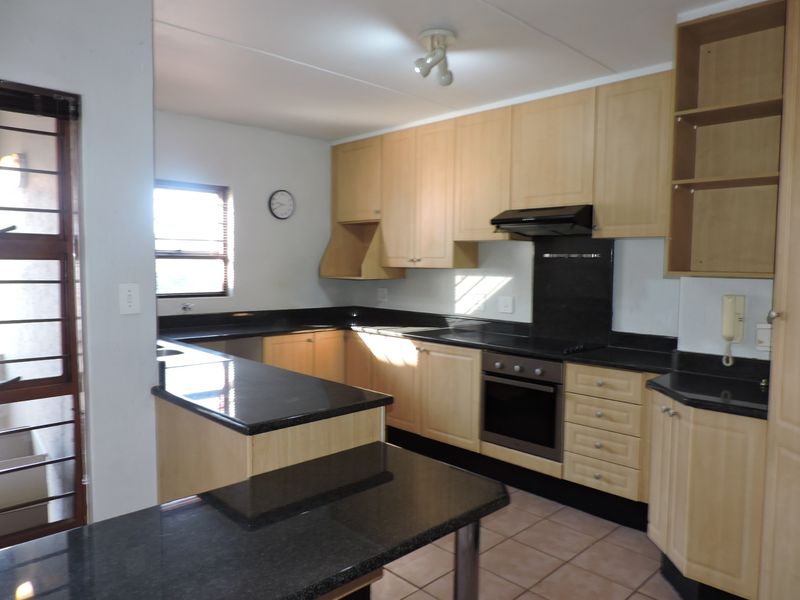 A functional kitchen featuring light wood cabinetry, dark granite countertops, built-in oven, extractor fan, and tiled flooring.