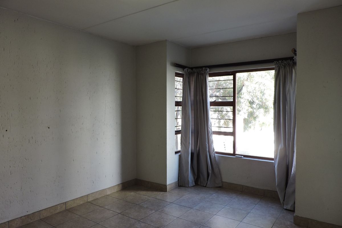 An empty bedroom featuring tiled flooring and a window with security bars, offering a blank canvas for potential interior design updates.