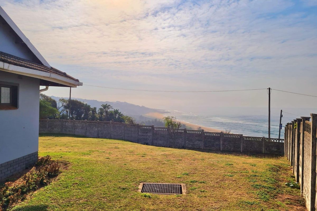 A rear garden area featuring a precast concrete boundary wall and a scenic coastal view overlooking the ocean.