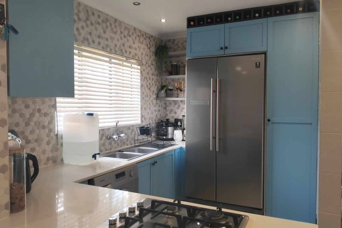 Modern kitchen featuring blue cabinetry, stone countertops, a gas hob, and a double stainless steel sink with a decorative hexagonal tiled backsplash.