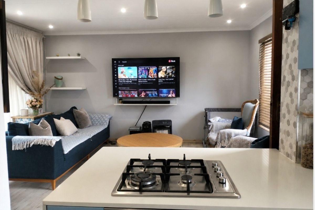 Open-plan living area featuring a modern kitchen island with a gas cooktop and built-in oven, overlooking a comfortable lounge space with neutral finishes.