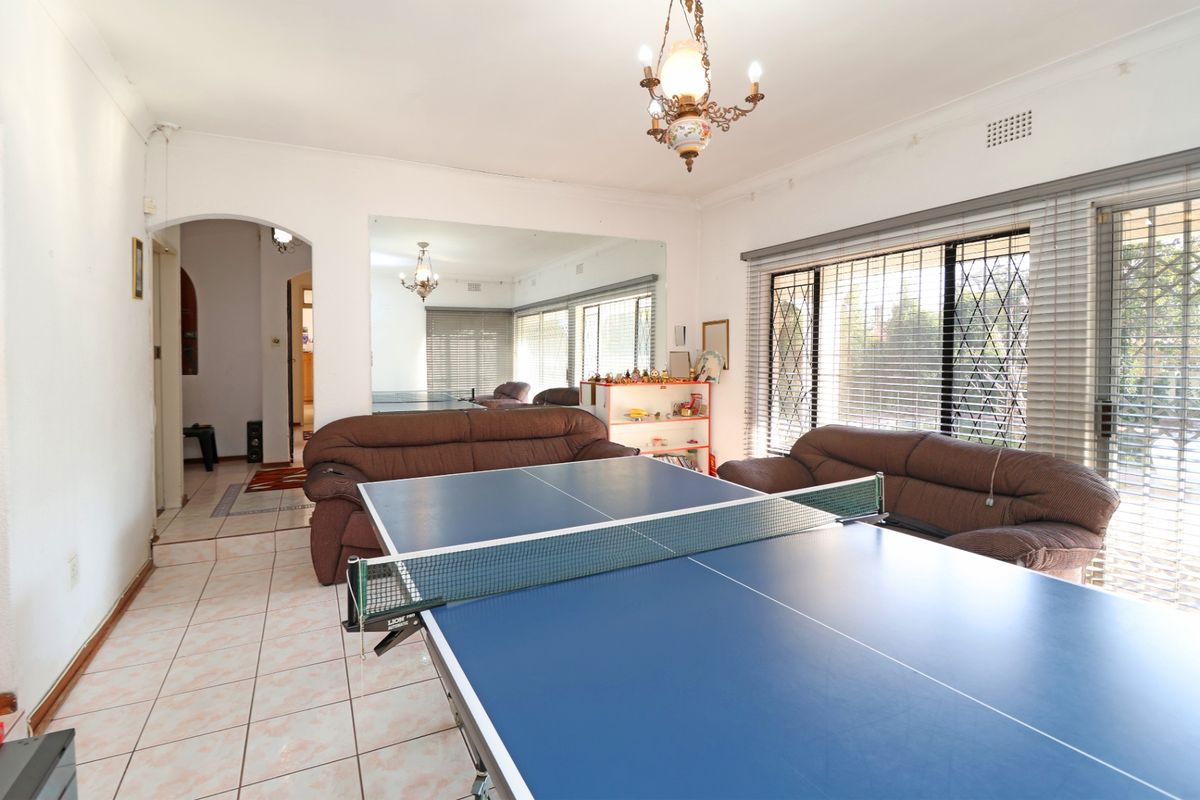 Spacious living area featuring tiled flooring, an arched entryway, and large windows with security bars, offering a versatile space for family living.