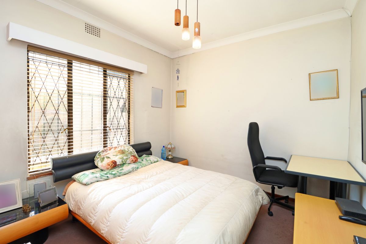 A functional bedroom featuring a window with security bars and venetian blinds, coved ceilings, and neutral wall finishes.