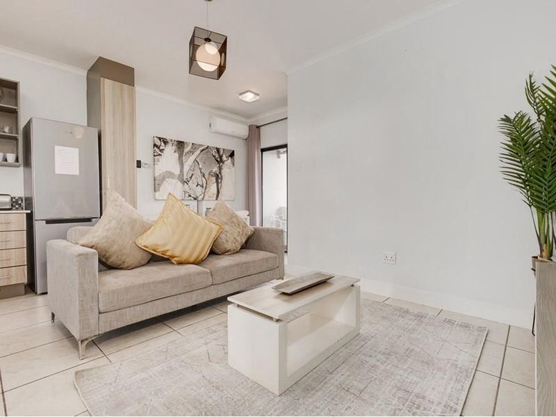 Modern open-plan living area featuring tiled floors, split-system air conditioning, and integrated kitchen cabinetry with contemporary finishes.