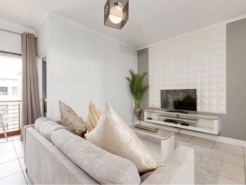 A bright living room featuring tiled floors, a textured feature wall, a floating media console, and direct access to a private balcony.