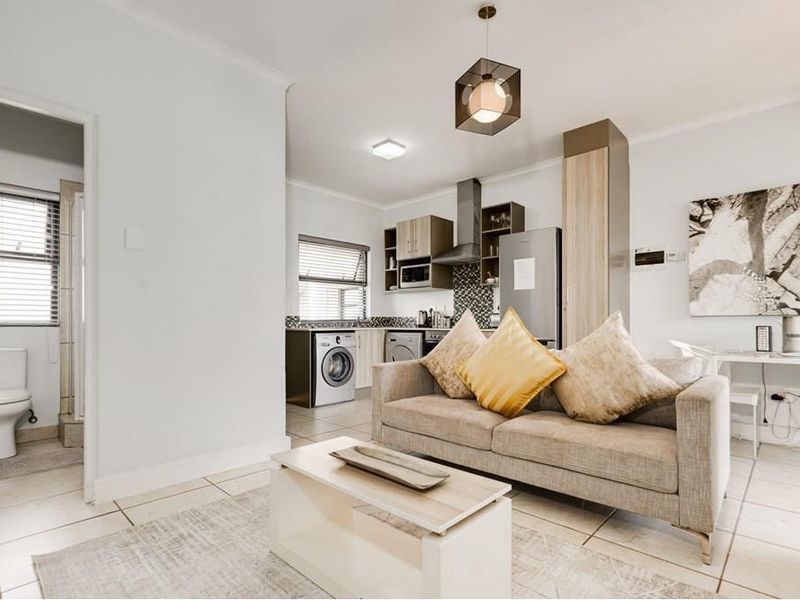 Modern open-plan apartment featuring a functional kitchen with built-in cabinetry, tiled flooring, and an adjacent bathroom with standard fixtures.