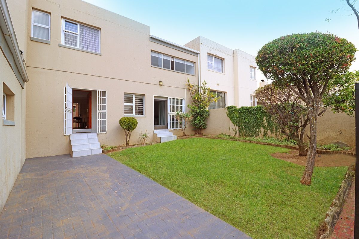Rear view of the cluster property featuring a paved patio area, a private lawn, and secure access points to the interior.