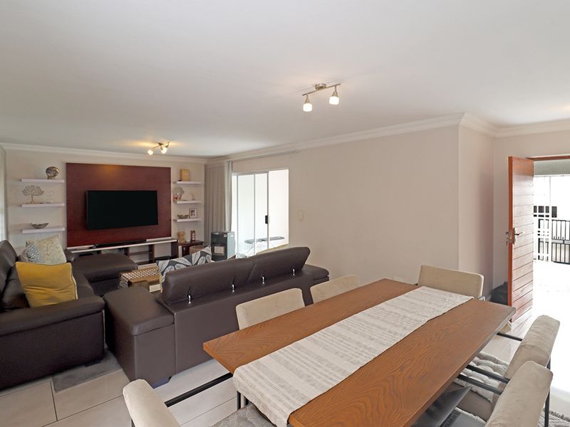 Spacious open-plan living and dining area featuring tiled floors, a decorative feature wall, and direct access to an outdoor patio through sliding glass doors.